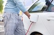 Mid section view of a mid adult man charging the electric car