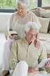 Senior man working on a digital tablet and his wife reading a magazine
