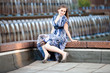 Beautiful young girl sitting near big fountain