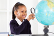 primary schoolgirl looking at globe using a magnifying glass