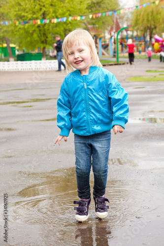Photo: A girl is jumping in the puddle A girl is jumping in the puddle