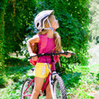 Children girl riding bicycle outdoor in forest smiling