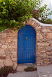 Wooden blue door in the stone wall and tree branches