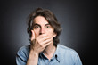 scared adult man with hand covering mouth and dramatic lighting