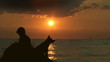 Boy and dog sitting near Sea at Sunset