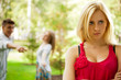Upset teenage girl being jeered by group of the other young peop