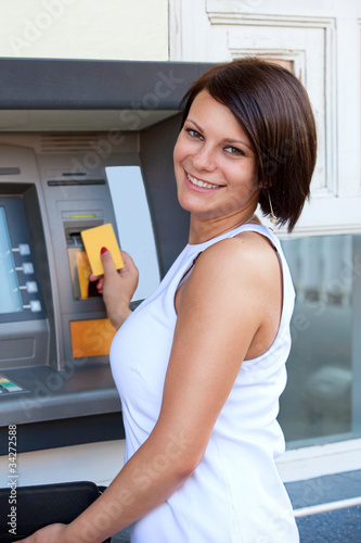 Photo: Woman withdrawing money from credit card at ATM Woman withdrawing money from credit card at ATM