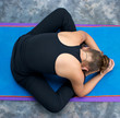 looking down on woman curled up in  bound angle forward fold pos