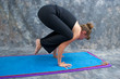 Photo: woman balancing on mat in studio doing yoga posture Bakasana or woman balancing on mat in studio doing yoga posture Bakasana or