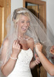 Bride putting on dress with veil
