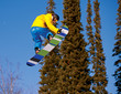 Snowboarder jumping through air with  blue sky in background