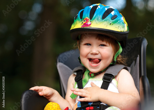 Photo: Little girl in the seat bicycle with a helmet on his head Little girl in the seat bicycle with a helmet on his head