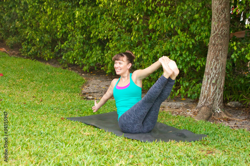 Photo: smiling woman doing Yoga pose Navasana variation or boat pose ou smiling woman doing Yoga pose Navasana variation or boat pose ou
