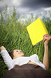 Woman lying in rapeseed field reading Woman lying in rapeseed field reading