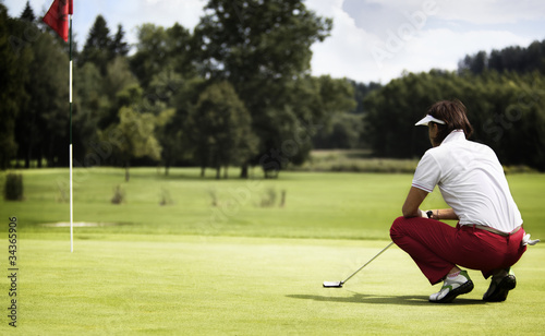 Photo: Woman examining green before putting. Woman examining green before putting.