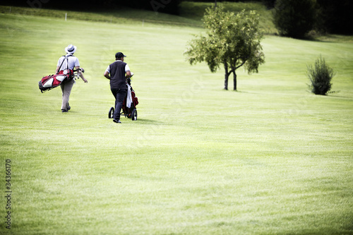 Photo: Men walking at golf course with bags. Men walking at golf course with bags.