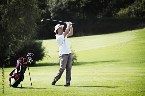 Photo: Golfer pitching at golf course. Golfer pitching at golf course.
