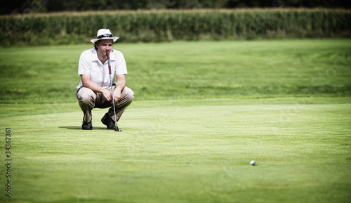 Photo: Golfer analysing green before putting. Golfer analysing green before putting.