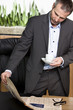 Businessman standing and reading newspaper in office.