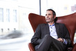 Business executive in red chair enjoying coffee.
