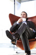 Office manager in red chair enjoying coffee.