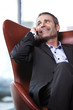 Office manager in red chair talking on cell-phone.