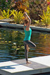 Photo: woman doing yoga outdoors in tree pose near water woman doing yoga outdoors in tree pose near water