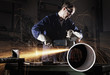 Photo: Worker cutting pipe with angel grinder. Worker cutting pipe with angel grinder.