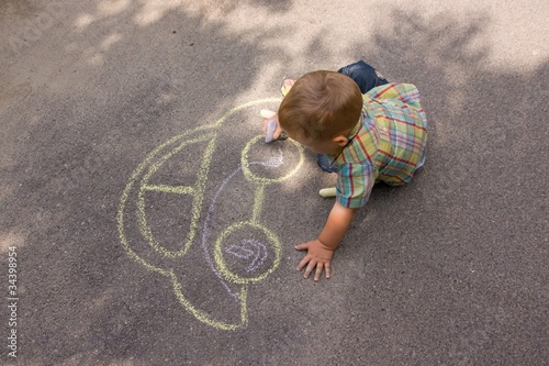 Foto: Boy drawing with chalk on the asphalt Boy drawing with chalk on the asphalt
