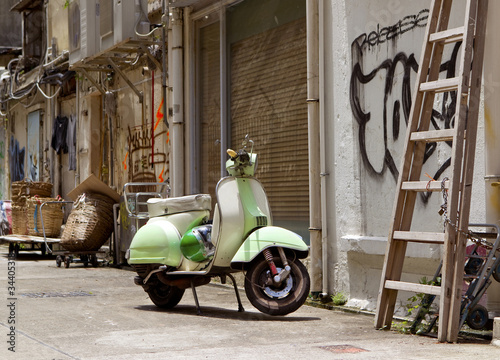 Photo: Classic green old scooter in back alley of downtown Hong Kong Classic green old scooter in back alley of downtown Hong Kong