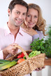 Couple smiling with vegetable basket.