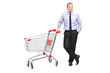 Photo: Full length portrait of a man posing next to an empty shopping c Full length portrait of a man posing next to an empty shopping c