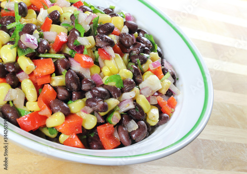 Photo: Southwest Black Bean Salad in a bowl sitting on a table. Southwest Black Bean Salad in a bowl sitting on a table.