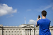 Photo: A young man taking a picture of Buckingham Palace A young man taking a picture of Buckingham Palace
