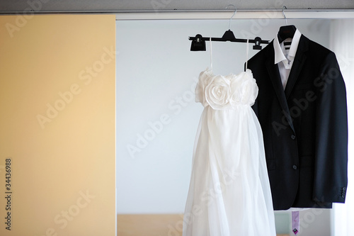 Photo: Wedding dress and a tuxedo hanging on a shoulders Wedding dress and a tuxedo hanging on a shoulders