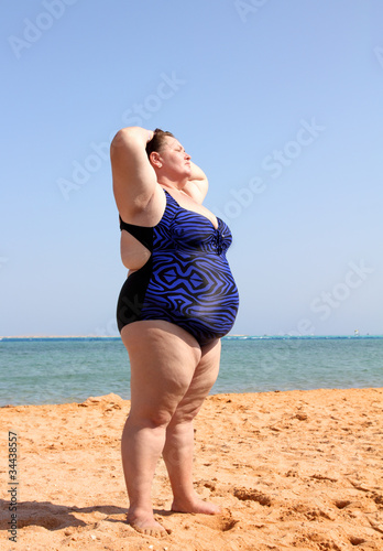 Foto: overweight woman on beach with hands up overweight woman on beach with hands up