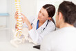 Foto: Female doctor pointing on bone in spine Female doctor pointing on bone in spine