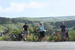 three bicycle tourists standing on road in mountains in Crimea, three bicycle tourists standing on road in mountains in Crimea,