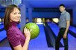 Girl holds ball for bowling and smiles, and man look at it