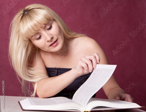 Photo: The girl on a chair reads the book The girl on a chair reads the book
