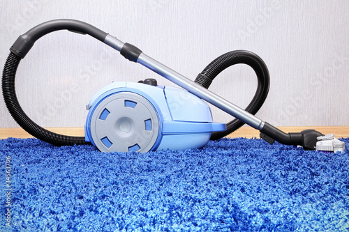 Photo: Vacuum cleaner stand on blue carpet. Vacuum cleaner stand on blue carpet.