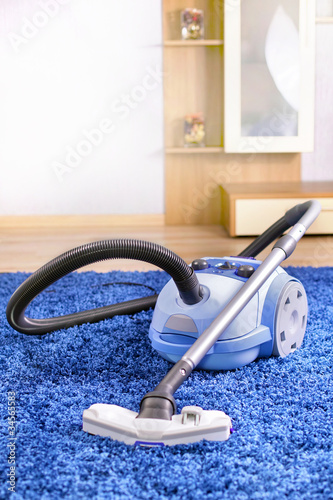Photo: Vacuum cleaner stand on blue carpet. Vacuum cleaner stand on blue carpet.