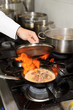 Chef is making flambe dish on restaurant kitchen Chef is making flambe dish on restaurant kitchen