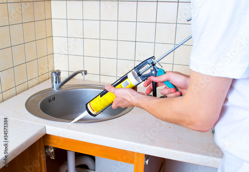 Photo: Caulking gun putting silicone sealant to installing a kitchen si Caulking gun putting silicone sealant to installing a kitchen si