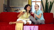 Two happy female friends eating popcorn and watching tv