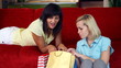 Two female friends with shopping bags lying on the sofa