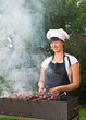 Young woman cook preparing meat in brazier Young woman cook preparing meat in brazier