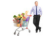 Man posing next to a shopping cart with groceries