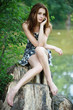 Photo: portrait of young woman sitting on stump and speaking on mobile portrait of young woman sitting on stump and speaking on mobile
