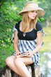 portrait of woman holding book and sitting on stump